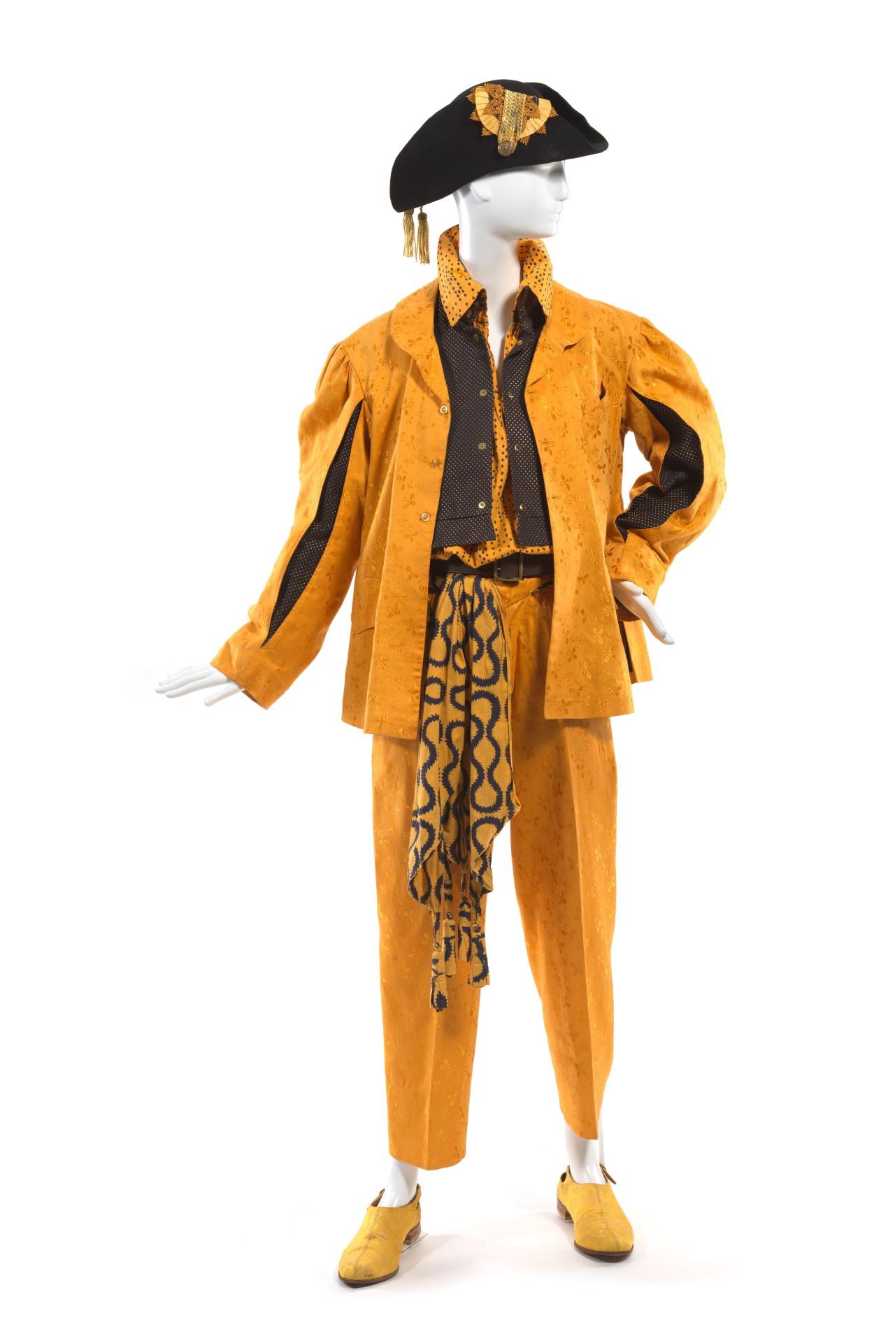 WORLDS END, London (retailer)<br />
 Vivienne WESTWOOD (designer)<br />
 Malcolm McLAREN (designer)<br/>
<em>Jacket, doublet, sash, shirt, trousers, belt, hat and shoes</em> 1981 {Pirate collection, autumn-winter 1981–82} <!-- (front view ) --><br />

cotton polyester (brocade, satin damask), cotton (brushed, thread, grosgrain), synthetic fabric (satin), wool (felt), nylon (lace), card, leather and plastic and metal (fastenings)<br />
(a) 72.0 cm (centre back) 66.0 cm (sleeve length) (jacket) (b) 46.0 cm (centre back) 52.5 cm (waist, flat) (doublet) (c) 42.0 x 223.0 cm (sash) (d) 86.5 cm (centre back) 49.0 cm (sleeve length) (shirt) (e) 104.0 cm (outer leg) 37.0 cm (waist, flat) (trousers) (f) 7.0 x 114.0 cm (belt) (g) 54.0 cm (outer circumference) 19.0 cm (height) 20.0 cm (width) (hat) (h-i) 9.0 x 10.0 x 29.0 cm (shoes) (each)<br />
National Gallery of Victoria, Melbourne<br />
Gift of Krystyna Campbell-Pretty AM and Family through the Australian Government’s Cultural Gifts Program, 2024<br />
2024.747.a-i<br />

<!--154144-->