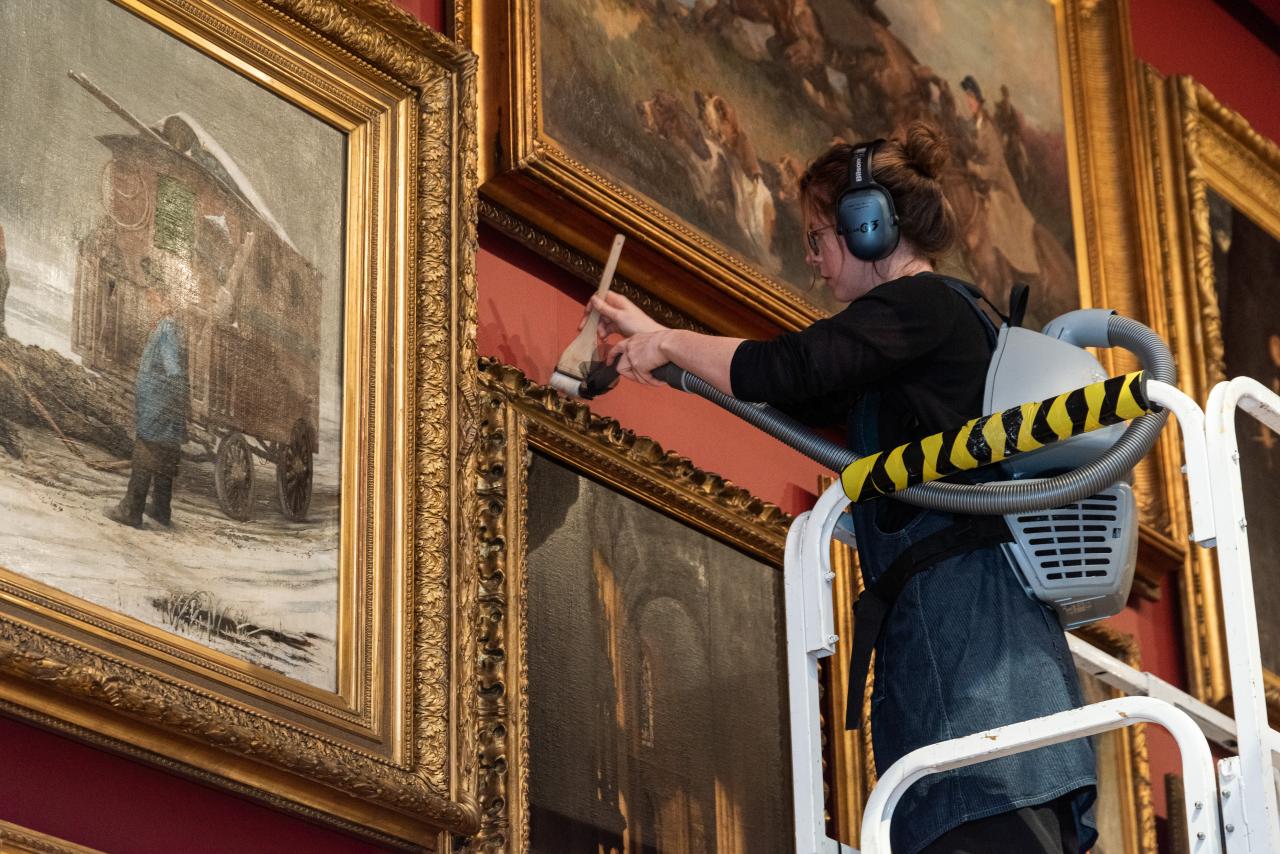 Conservator brush vacuuming frames in NGV’s Salon room<br/>