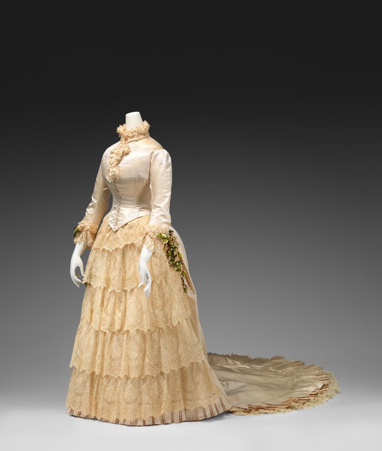 UNKNOWN, Australia<br/>
<em>Wedding dress</em> 1885 <!-- (front 3/4 left) --><br />

silk (satin), cotton, wax flowers<br />
(a) 54.0 cm (centre back) 27.5 cm (waist, flat) (bodice) (b) 209.0 cm (centre back) 28.0 cm (waist, flat) (skirt)<br />
National Gallery of Victoria, Melbourne<br />
Gift of Mr J. G. H. Sprigg, 1971<br />
D100.a-b-1971<br />

<!--45280-->