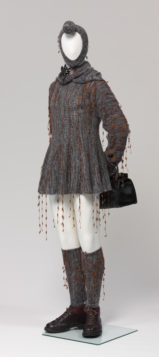 HOUSE OF REX, MICHAEL GLOVER KNITS, Melbourne (fashion house)<br />
 HOUSE OF REX, Melbourne (retailer)<br />
 Michael GLOVER (designer)<br />
 Douglas McMANUS (designer)<br/>
<em>Nordic salesman in swing dress wearing showgirl choker</em> (1994) <!-- (front 3/4 left ) --><br />

wool, silk, cotton, chenille, leather, metal, rubber, acrylic<br />
(a) 79.9 cm (centre back) 41.3 cm (waist, flat) (dress) (b) 35.0 x 24.5 cm (balaclava) (c-d) 50.0 x 15.0 cm (each) (leggings) (e-f) 30.0 x 11.5 x 14.5 cm (each) (boots) (g) 31.0 x 20.0 x 24.0 cm (bag) (h) 88.0 x 10.0 cm (stirrup strap) (i) 4.2 x 25.3 x 2.5 cm (bracelet) (j) 2.0 x 46.5 x 8.0 cm (choker)<br />
National Gallery of Victoria, Melbourne<br />
Purchased, 1994<br />
CT426.a-j-1994<br />

<!--55874--><br/><a class="col-link block" href="/explore/collection/work/55874"><strong>Collection page <i class="fa fa-angle-right"></i></strong></a>