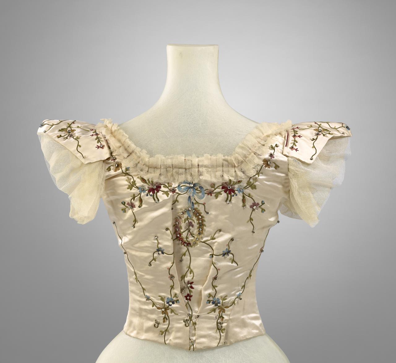 MRS EELES, Melbourne (dressmaker)<br/>
<em>Evening bodice</em> (c. 1900) <!-- (back view) --><br />

satin (silk), silk thread, diamanté, metal, baleen<br />
30.5 cm (centre back) 13.0cm (sleeve length)<br />
National Gallery of Victoria, Melbourne<br />
Gift of Miss Bell, 1973<br />
D244-1973<br />

<!--45458-->