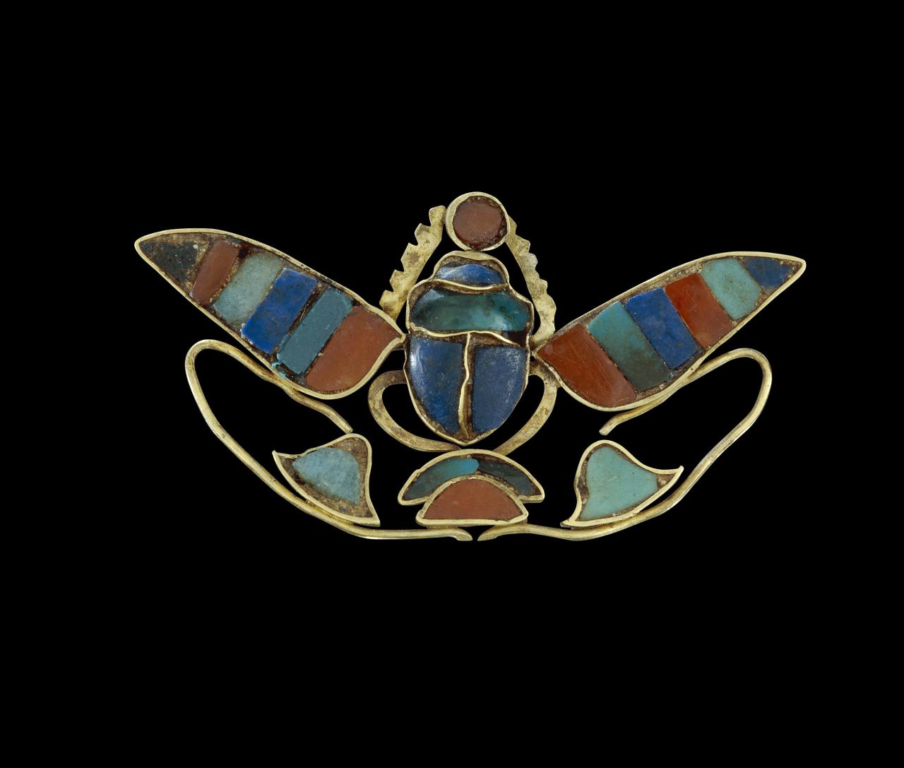 Ornament of a winged scarab holding a sun-disc​, depicting the throne name of King Senusret II <br/>
possibly Egypt, Thebes <br/>
12th Dynasty, reign of Senusret II, about 1880–1874 BCE   <br/>
electrum, lapis lazuli, cornelian, feldspar <br/>
H 1.8cm, W 3.5cm, D 3cm​ <br/>
​British Museum, London <br/>
EA54460<br/>
© The Trustees of the British Museum