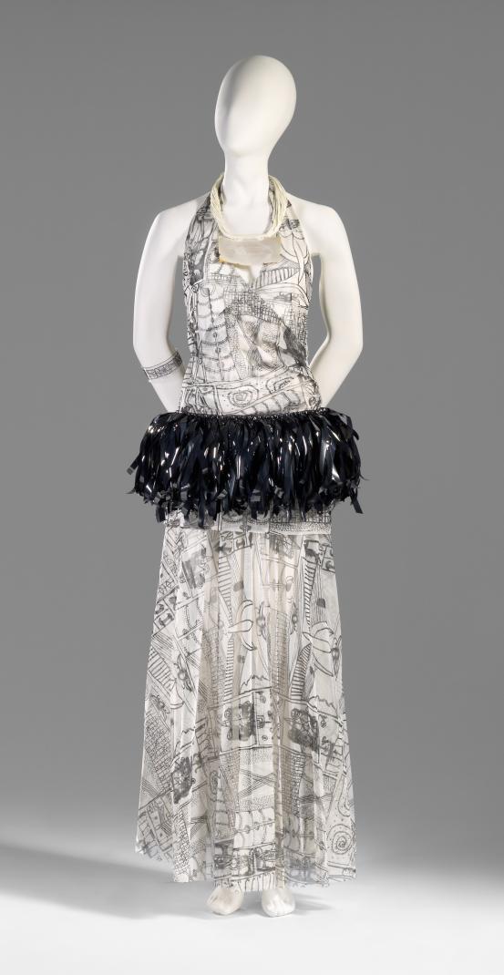 DORIS DE PONT, Auckland (fashion house)<br />
 Doris DE PONT (designer)<br />
 Margo BARTON (milliner)<br />
 Sofia TEKELA-SMITH<br/>
<em>Outfit: Habanero halter top, Pacific pleats skirt, Hibiscus, feather and Pule headpiece and Towards a ship of new arrivals... necklace</em> 2003 {Let’s gather here collection, winter 2004} <!-- (front view) --><br />

polyester, video tape, transparent synthetic polymer resin, vinyl, cotton thread, mother-of-pearl<br />
(a) 55.0 cm (centre back) 37.0 cm (waist, flat) (top) (b) 97.0 (centre back) 37.5 cm (waist, flat) (skirt) (c) 25.0 cm (height) 46.0 cm (waist, flat) (titi) (d) 7.5 x 18.0 x 29.0 cm (headpiece) (e) 28.5 x 18.0 x 1.6 cm (necklace) (f) 4.0 x 8.0 x 7.5 cm (bangle)<br />
National Gallery of Victoria, Melbourne<br />
Purchased NGV Foundation, 2008<br />
2008.248.a-f<br />

<!--87053--><br/><a class="col-link block" href="/explore/collection/work/87053"><strong>Collection page <i class="fa fa-angle-right"></i></strong></a>