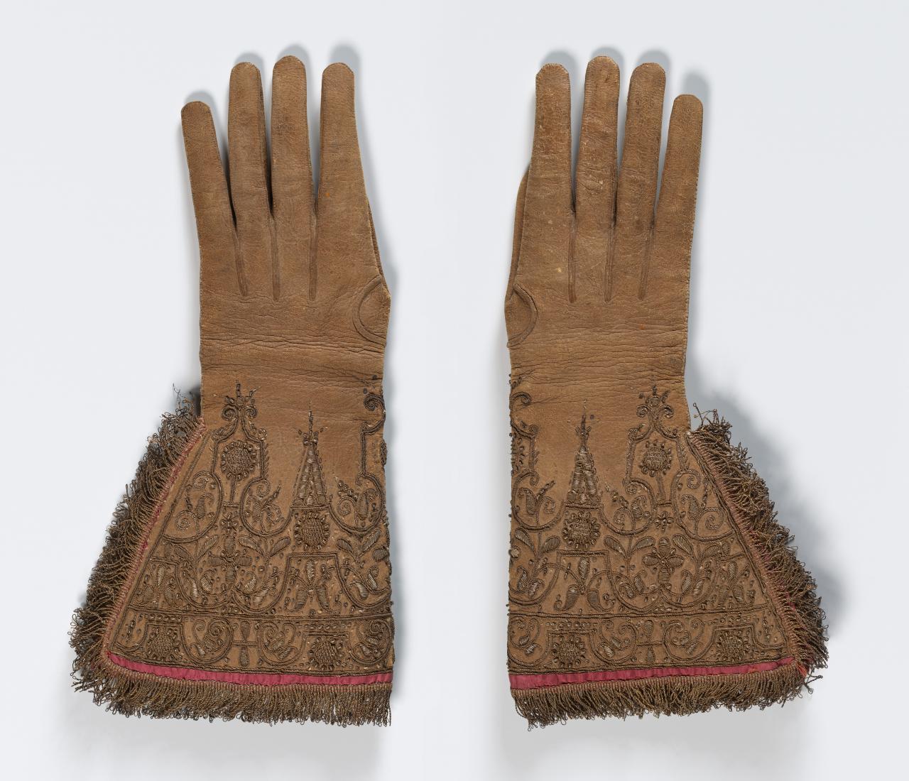 (ENGLAND / THE NETHERLANDS)<br/>
<em>Gloves</em> (c. 1620) <!-- (group) --><br />

leather, silk (lining, thread), gilt metal (thread, fringe, spangles)<br />
(a) 41.0 x 20.0 cm (b) 40.4 x 20.0 cm<br />
National Gallery of Victoria, Melbourne<br />
Purchased, 1956<br />
1658G.a-b-D4<br />

<!--51543-->