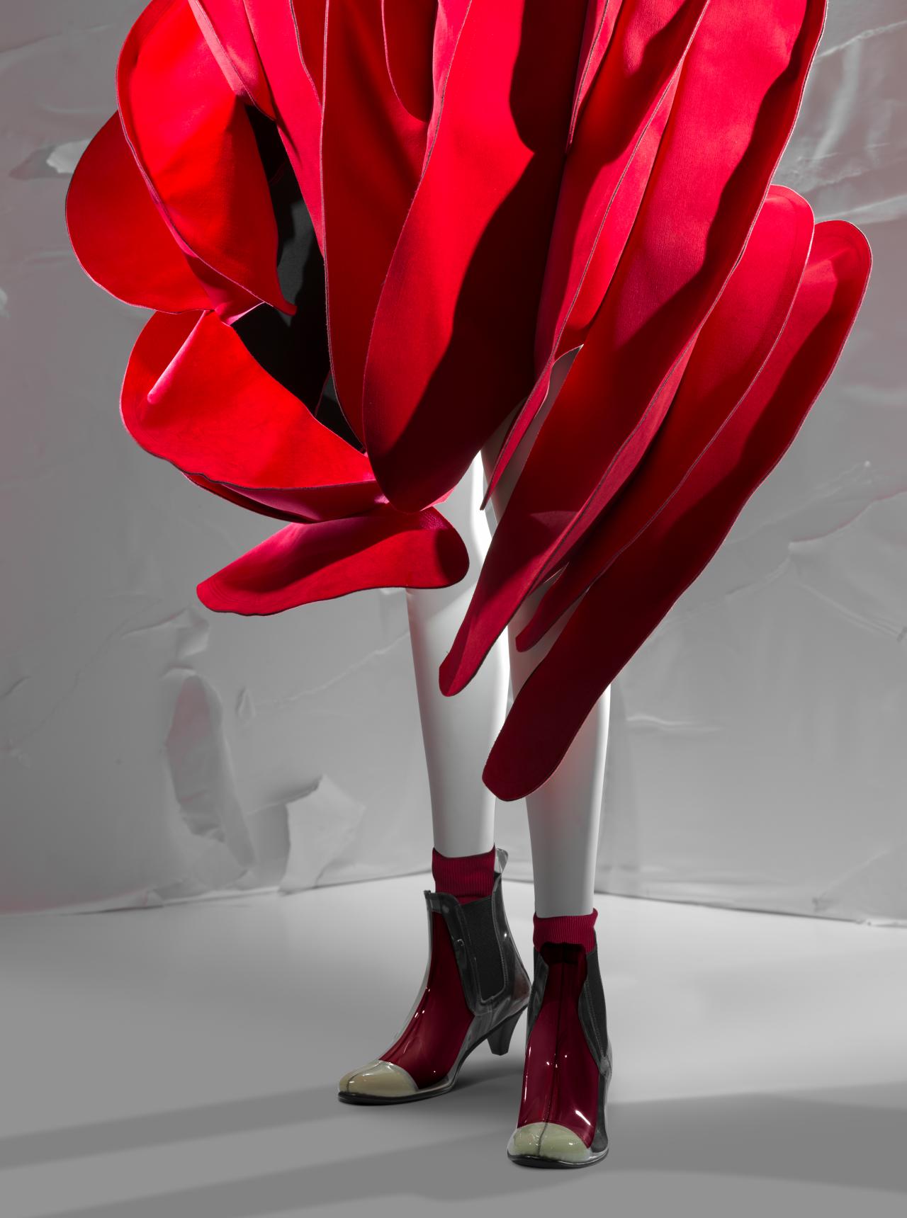 COMME DES GARÇONS, Tokyo (fashion house)<br />
 Rei KAWAKUBO (designer)<br/>
<em>Cape, shorts, socks and boots </em> 2014 {Blood and Roses collection, spring-summer 2015} (detail)<br />

cotton, polyester, synthetic leather, nylon, plastic, elastic, rubber<br />
(a) 141.0 cm (centre back) 138.0 cm (hem circumference) (cape) (b) 34.0 cm (waist, flat) 14.5 cm (outer leg) (shorts) (c-d) 27.0 x 24.0 x 0.2 cm (each) (socks) (e-f) 9.0 x 9.5 x 27.5 cm (each) (boots)<br />
National Gallery of Victoria, Melbourne<br />
Gift of Takamasa Takahashi and David Tune, 2020<br />
2020.815.a-f<br />
© Comme des Garçons
<!--141052-->